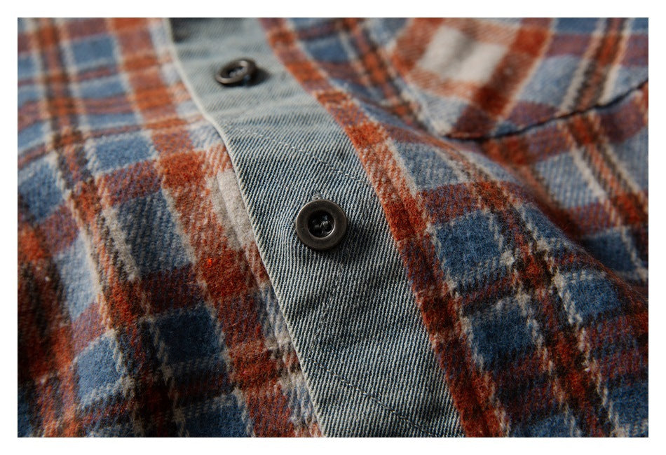 Close-up of dark buttons on the gray placket, set against rust, blue, and cream plaid fabric.