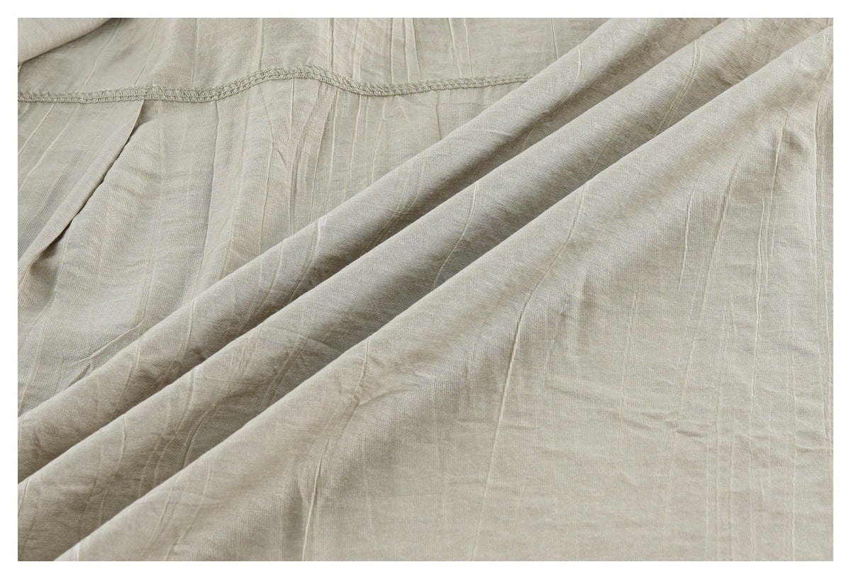 Close-up of beige shirt fabric folds and an overlocked seam, showing its subtle vertical texture.