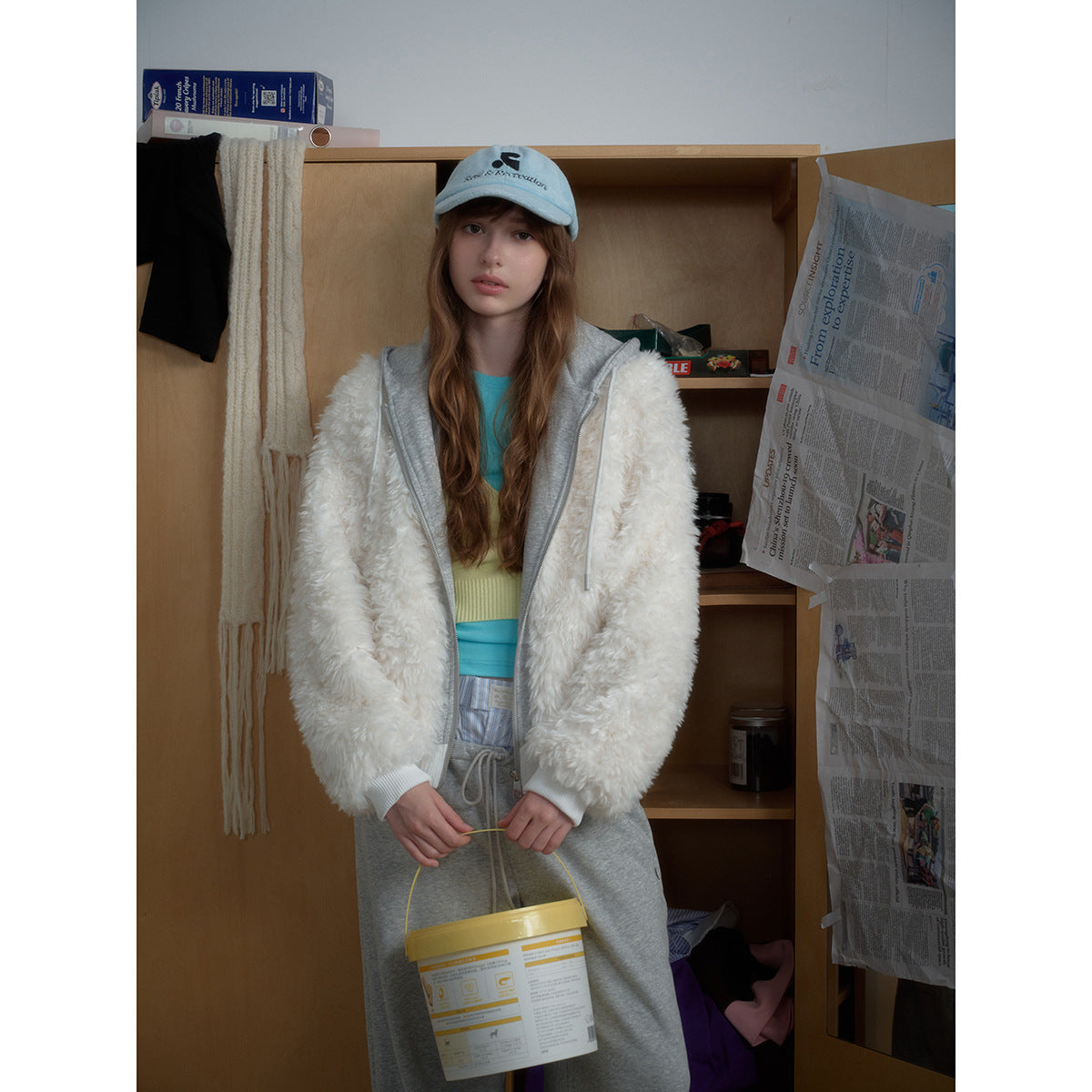 Front view of a model wearing an open white fluffy hoodie over a gray hooded layer and gray sweatpants.