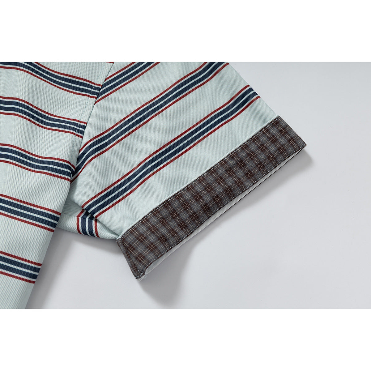 Close-up of the striped polo's short sleeve, finished with a brown plaid cuff.