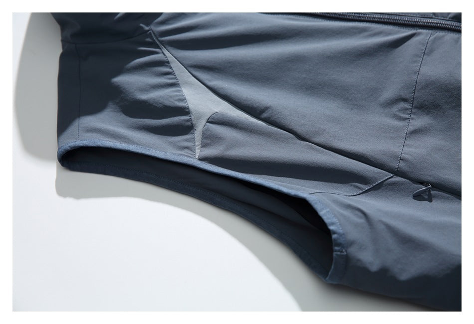 Close-up of the slate-blue vest's side and underarm seam construction with curved paneling.
