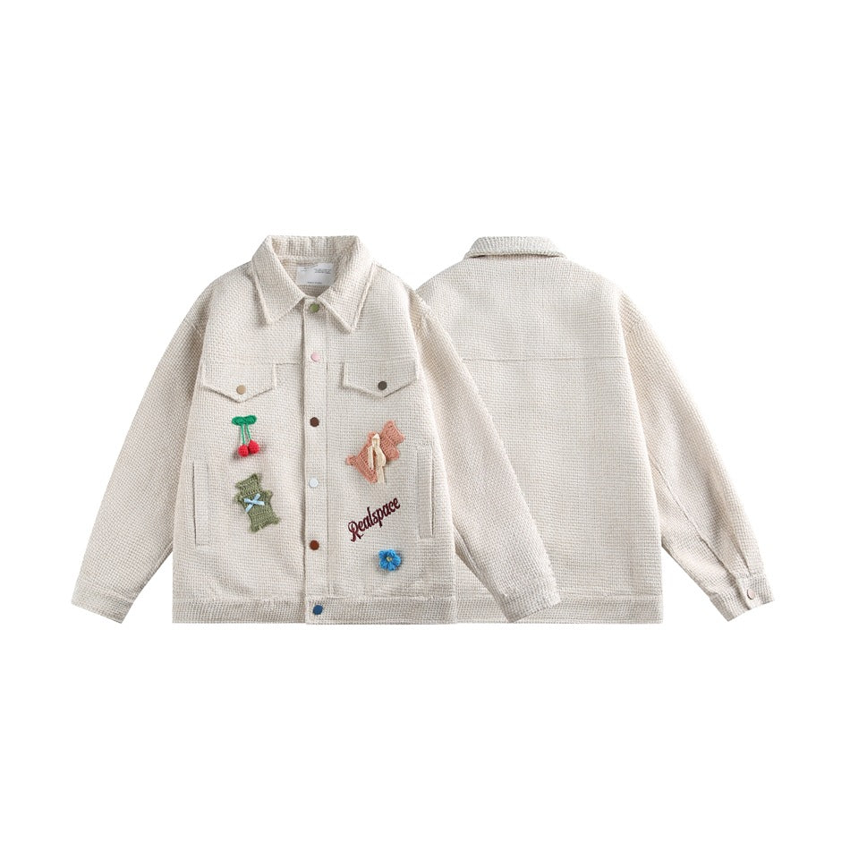 Cream jacket shown front and back, with chest pockets, colorful buttons, and embroidered patches on the front.