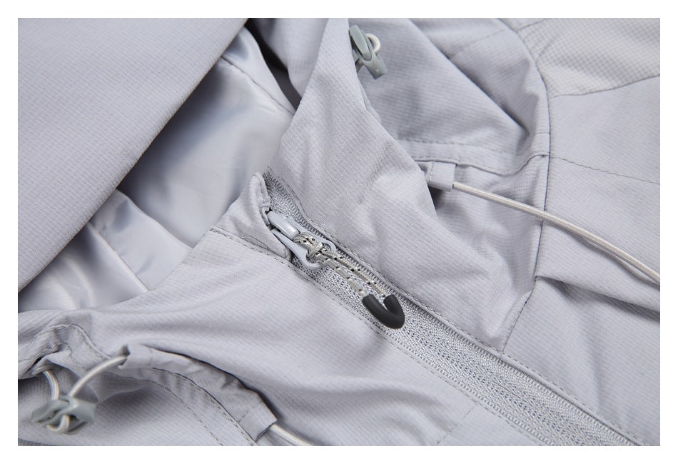 Close-up of the pale gray jacket's front zipper, hood fabric, and drawcord adjusters.