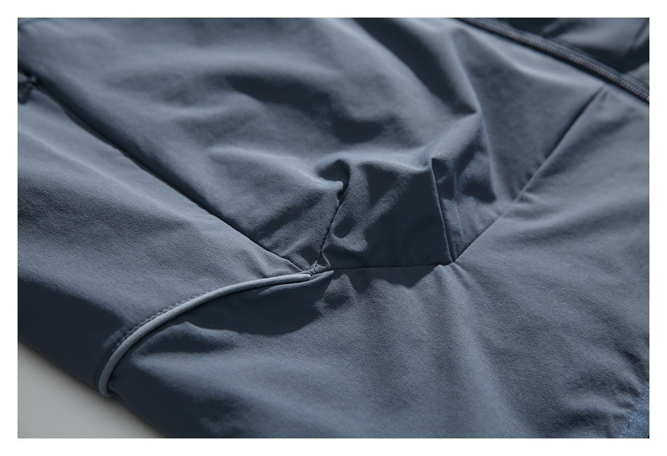 Close-up of gathered slate blue-gray fabric and shaped panel seams near a bound edge.
