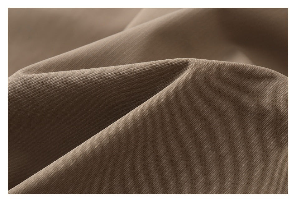 Macro view of beige fabric draped in soft folds, showing a fine woven texture.