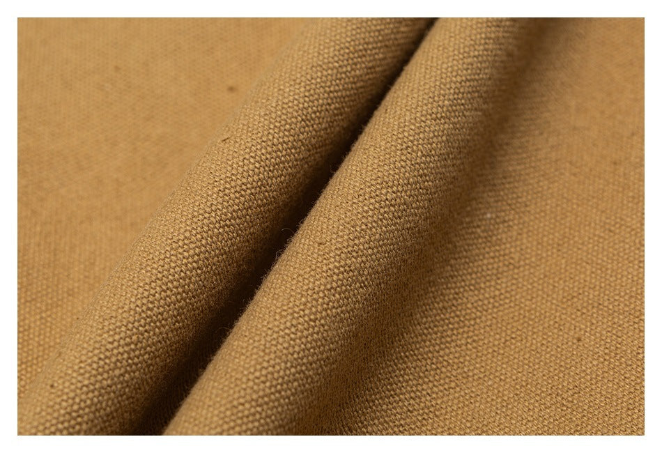 Close-up of camel-brown woven fabric with a visible textured weave and soft folds.