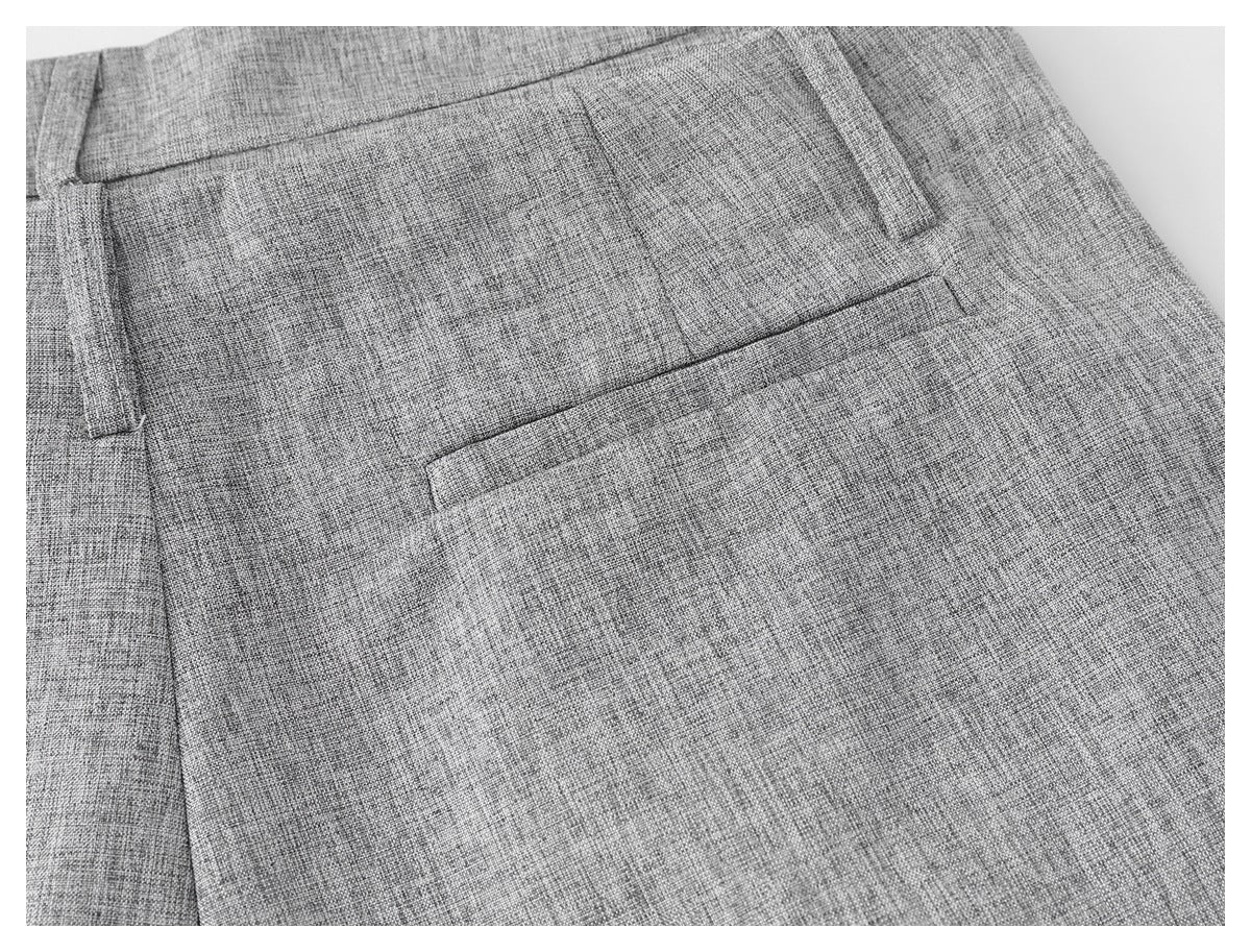 Close-up of a welt pocket and belt loop on light gray textured trousers.