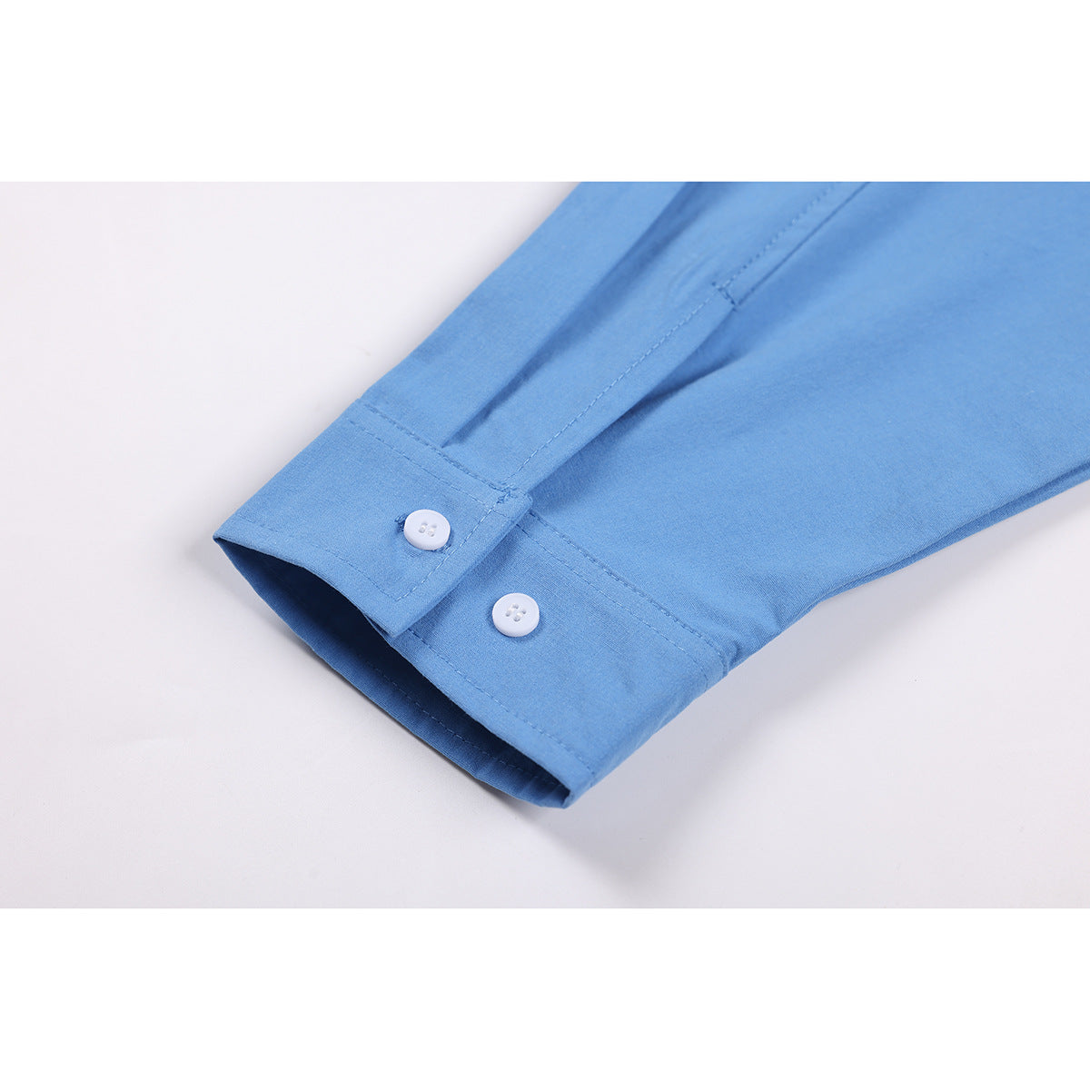 Close-up of a light blue shirt cuff with two white buttons.