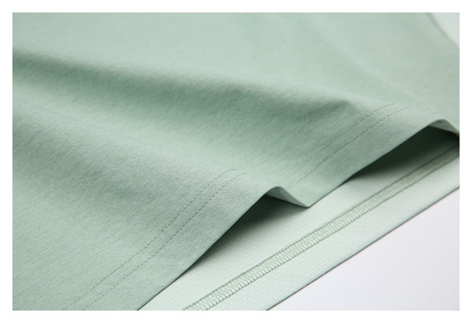 Close-up of the shirt's mint green fabric and stitched bottom hem, showing the pale underside.