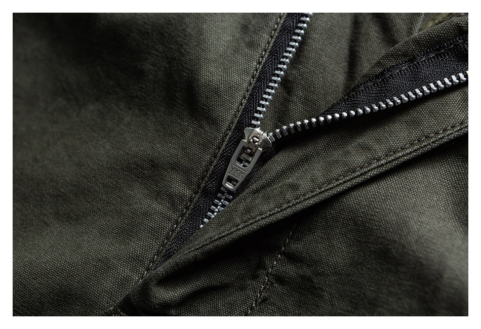 Close-up of a partly open metal zipper on dark olive trousers.