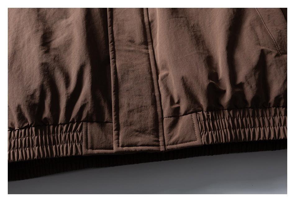 Close-up of the brown jacket's gathered hem and overlapping front closure.