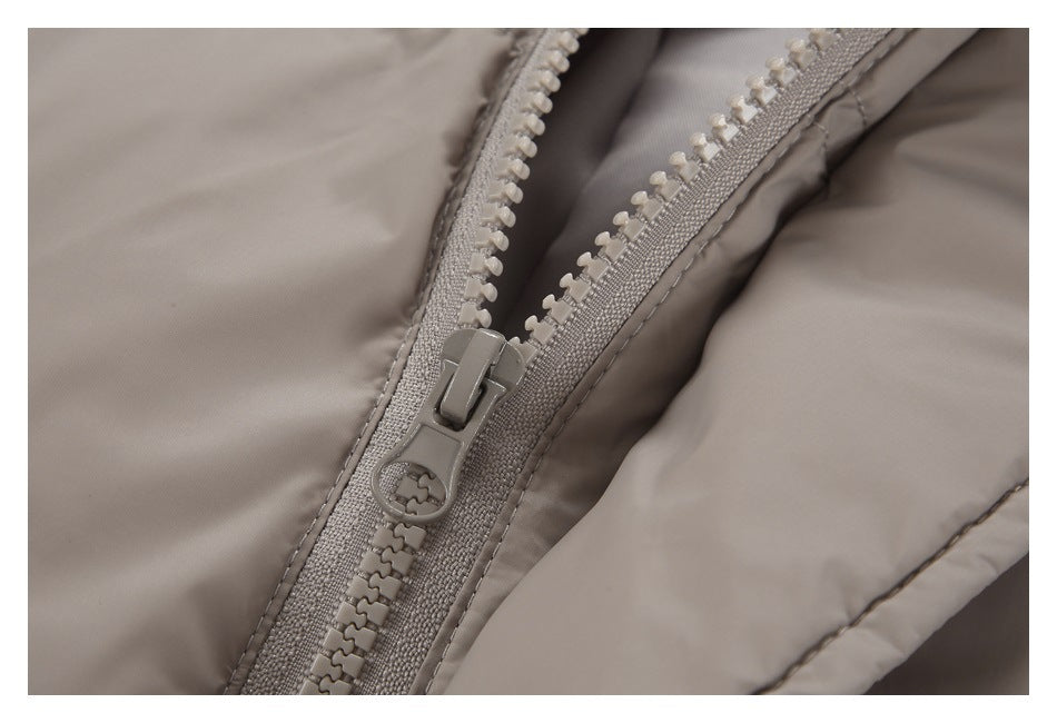 Close-up of a taupe jacket’s chunky front zipper and stitching.