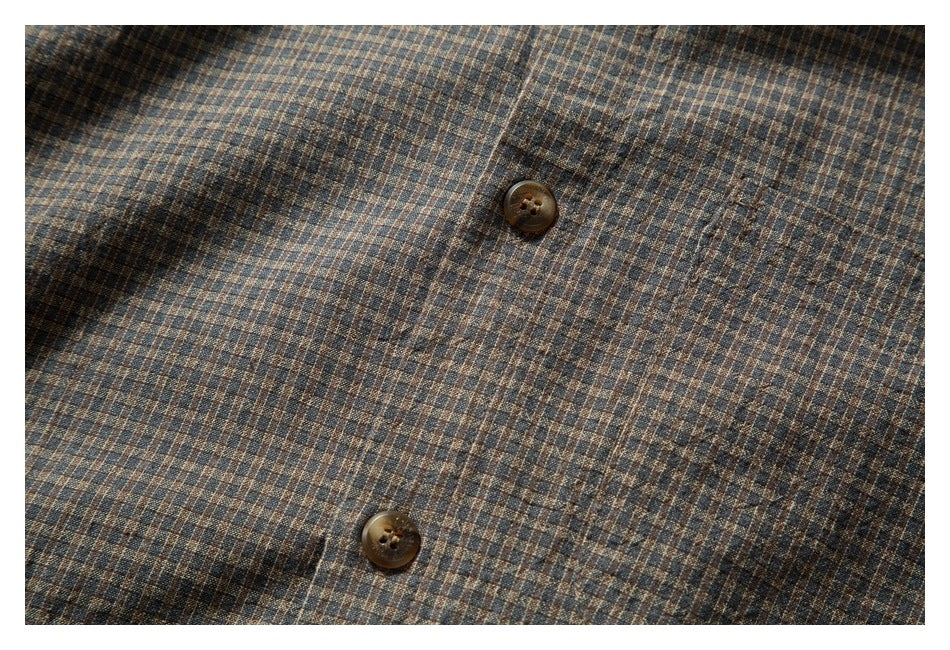 Close-up of two brown buttons on the front of a brown and blue small-check shirt.