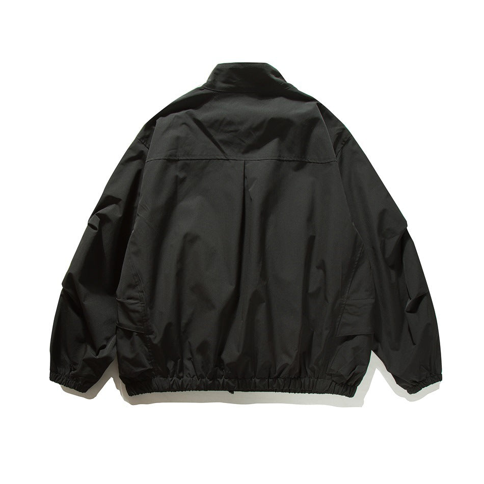 Back view of a black jacket with a stand collar, back yoke, and gathered cuffs and hem.