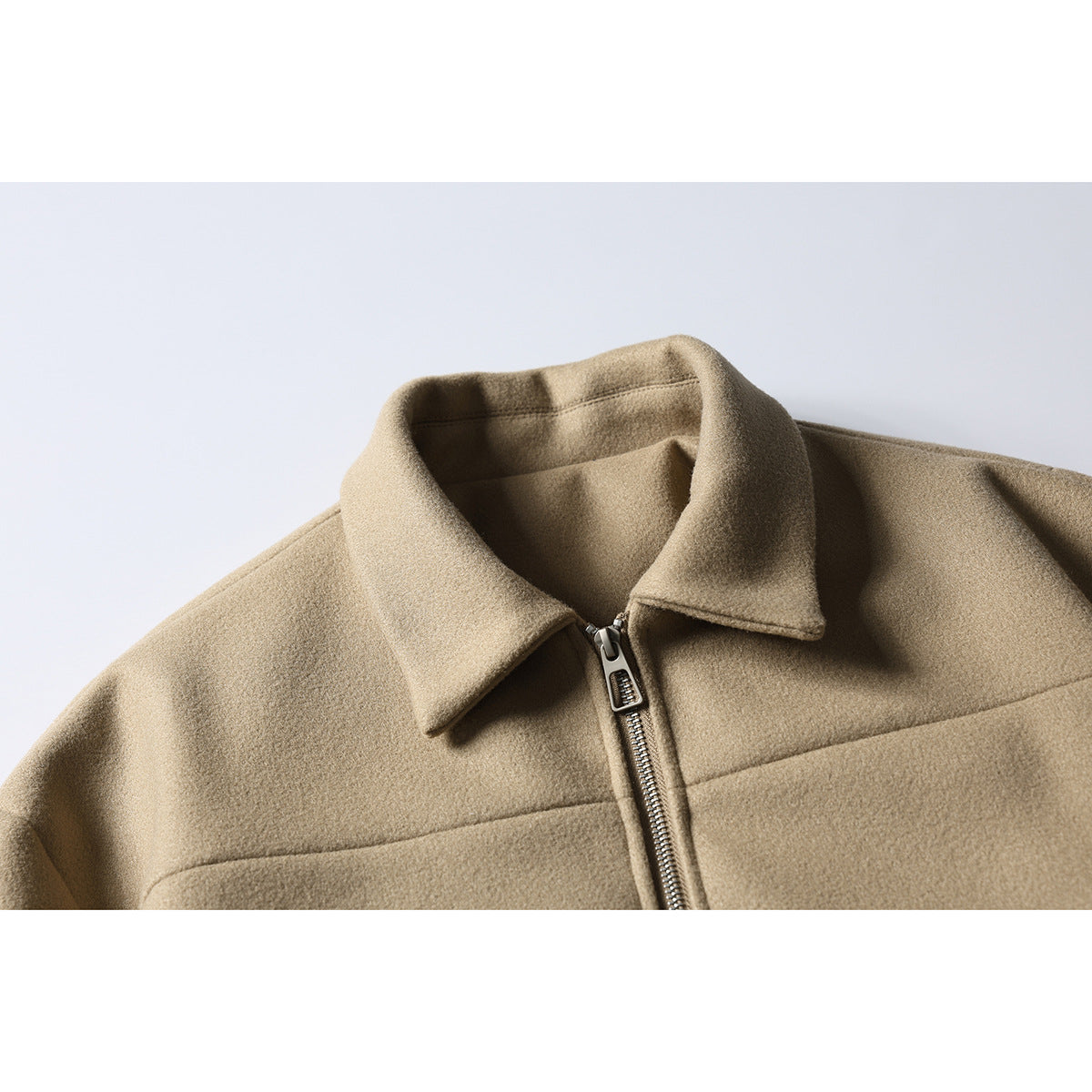 Close-up of a tan jacket's wide collar, front zipper, and upper chest seam.
