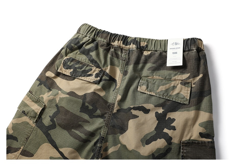 Cropped rear view of camouflage cargo shorts with an elastic waistband and two flap pockets.