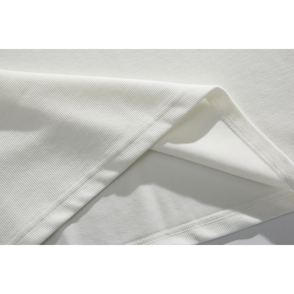 Close-up of the folded hem and stitching on a white ribbed shirt.