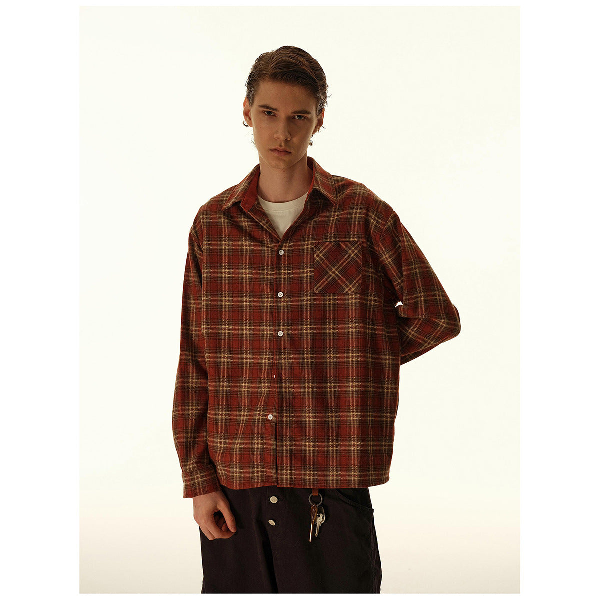 Model wearing a rust-red and brown plaid button-up shirt with a single chest pocket and white buttons.