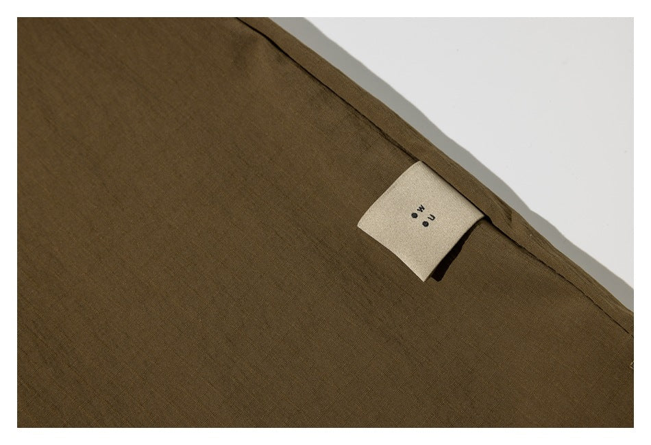 Close-up of an olive-brown garment seam with a small beige fabric label.