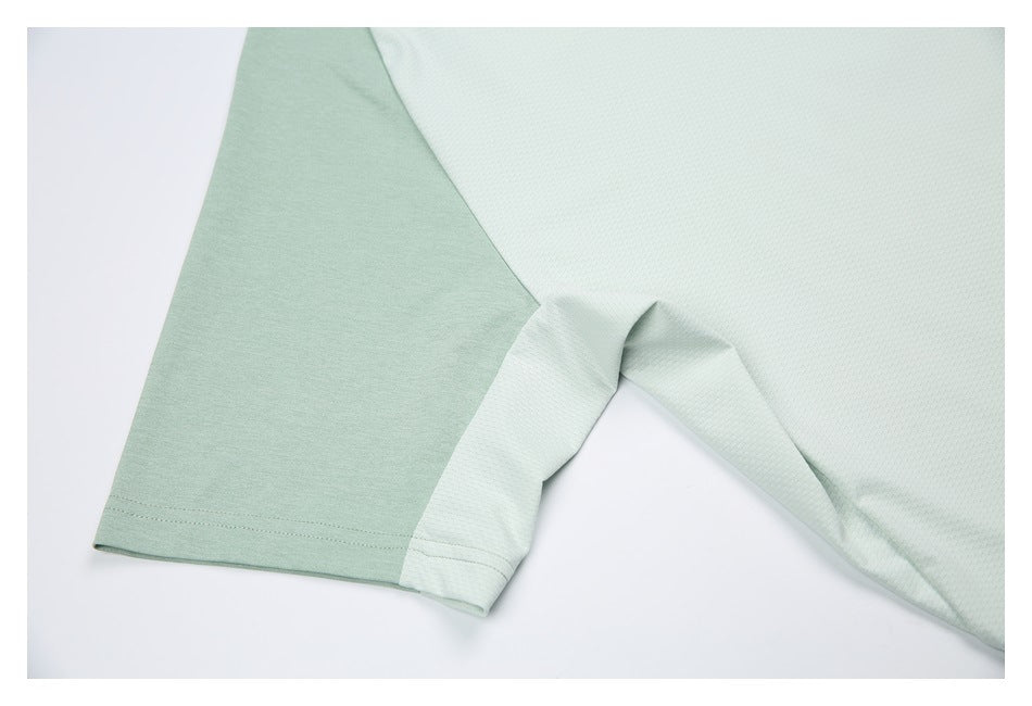 Close-up of the shirt's side and underarm seam where pale sage fabric meets a lighter textured panel.