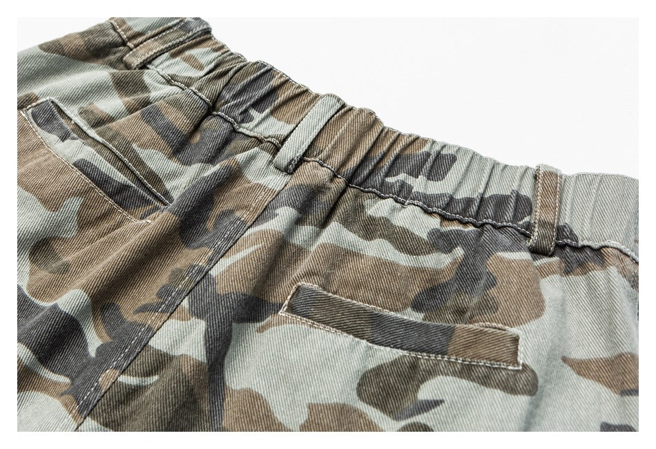 Close-up of camouflage trousers showing the elastic waistband, belt loops, and a pocket.