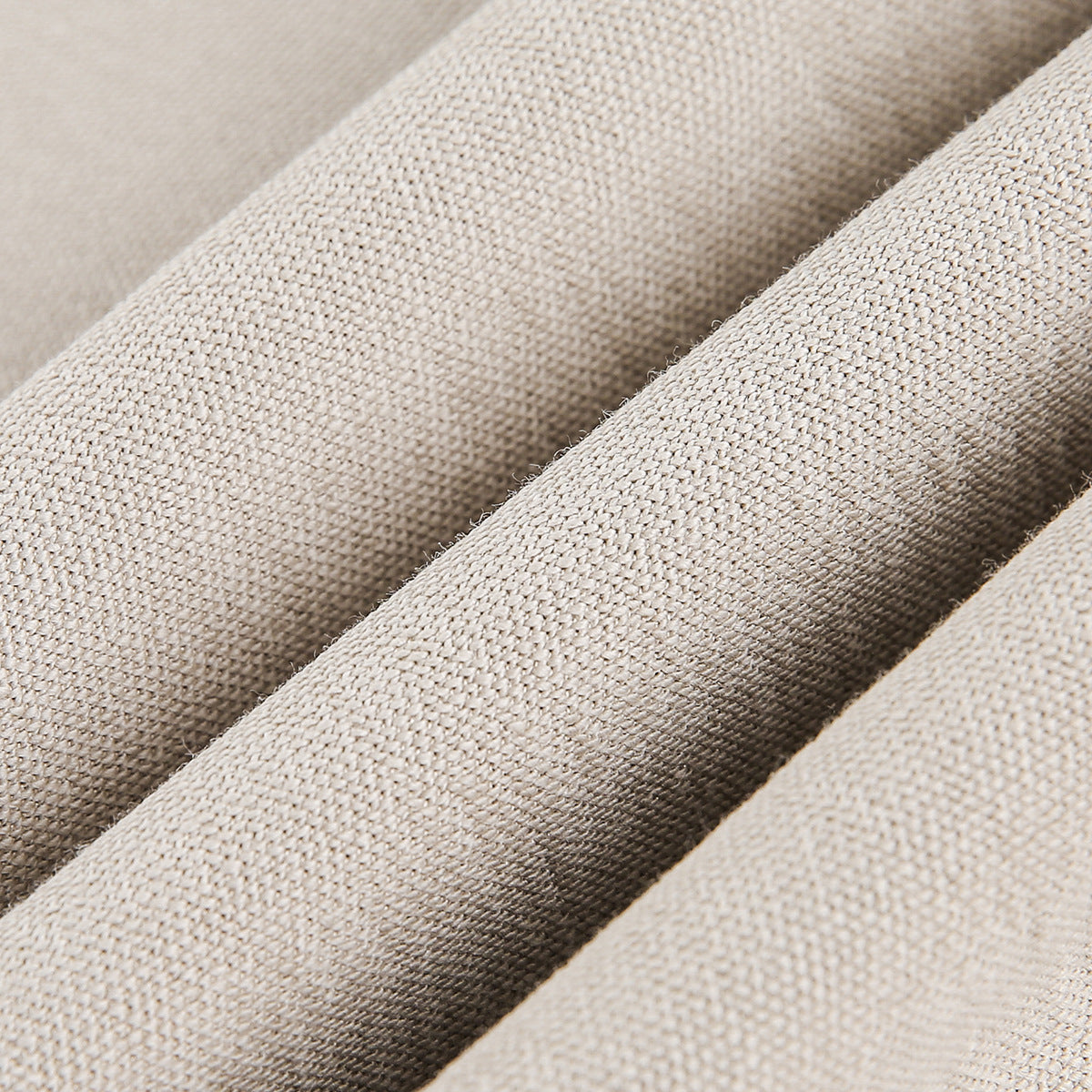 Close-up of beige fabric arranged in folds, showing its textured surface.