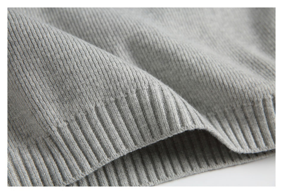 Close-up of a folded ribbed edge and knit texture on a light gray garment.