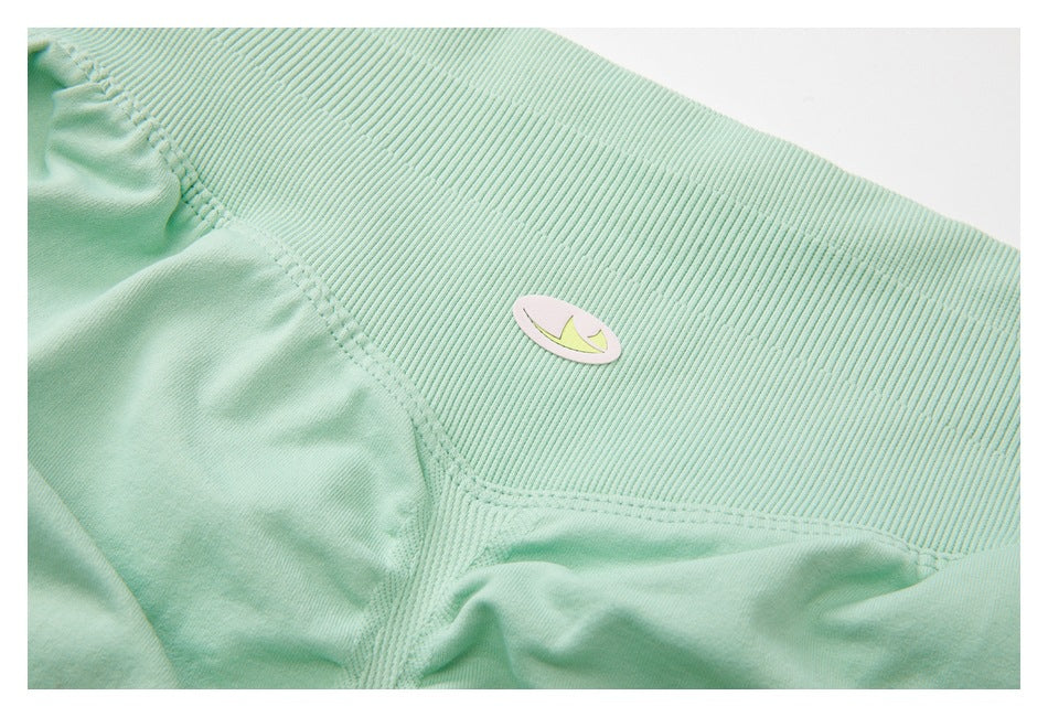 Close-up of the mint-green leggings’ ribbed waistband, seams, and small oval emblem.