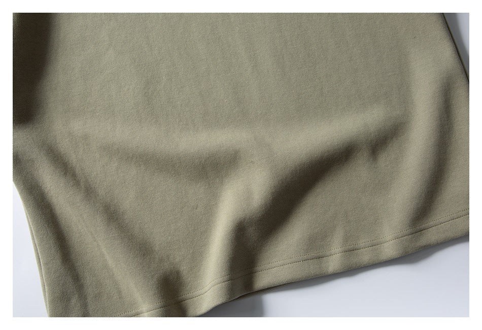 Close-up of the stitched bottom hem on a muted olive-beige garment.
