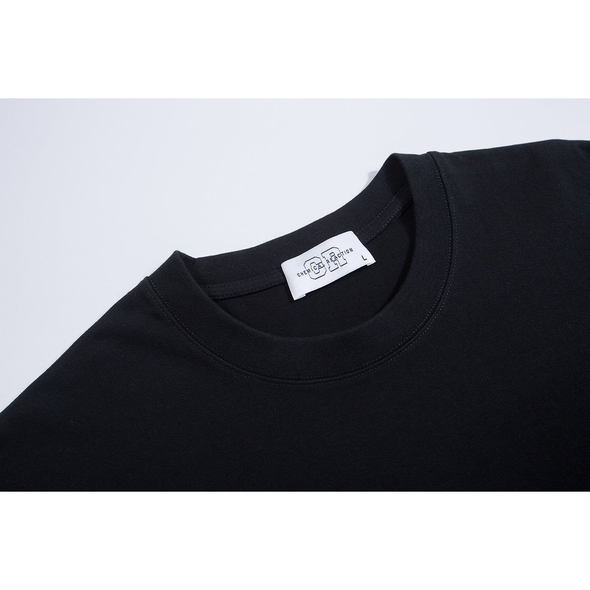 Close-up of a black T-shirt crew neckline with a white sewn-in label.
