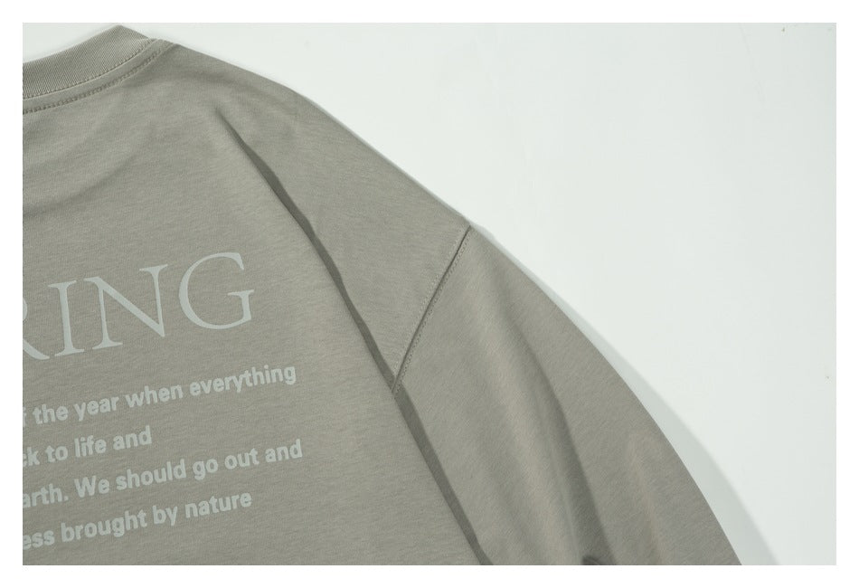 Close-up of the light gray shirt's back shoulder and sleeve seam, with part of the white graphic visible.