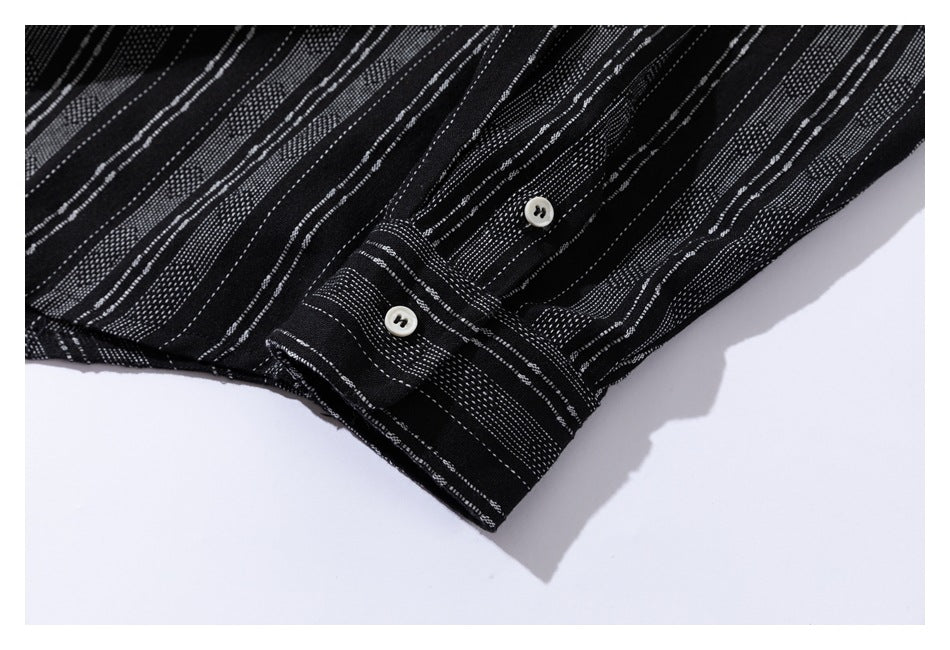 Close-up of a striped black sleeve cuff with white buttons and matching white-dashed fabric.