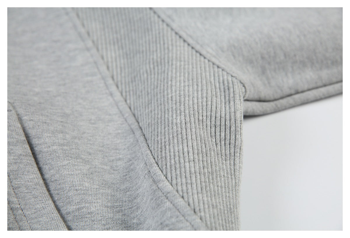 Close-up of a light gray sweatshirt seam beside a vertically ribbed panel.