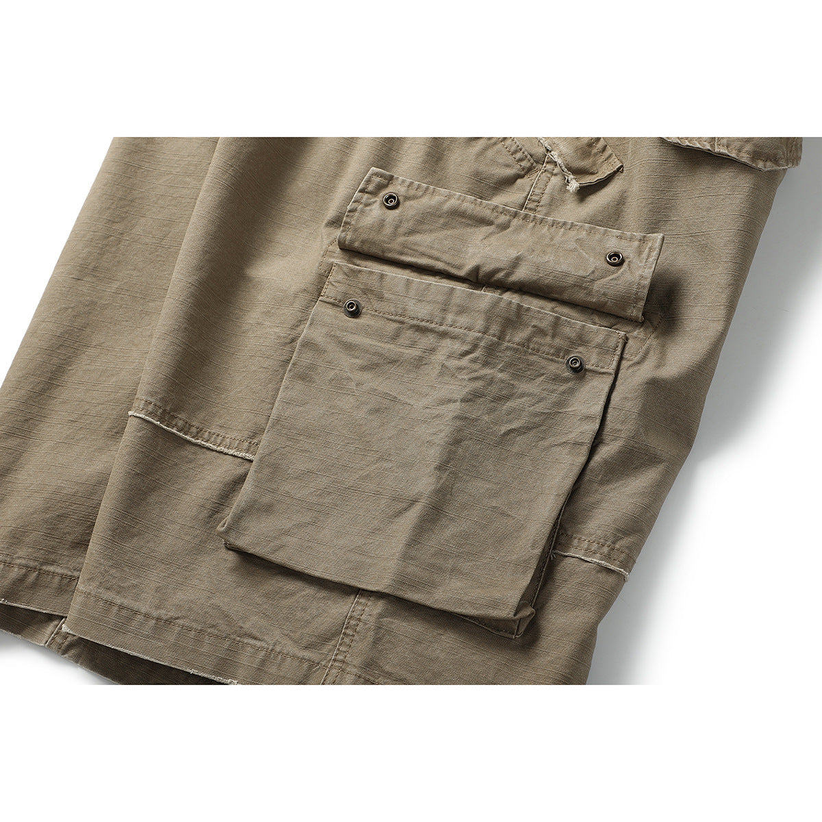 Close-up of a large button-flap cargo pocket on taupe shorts.