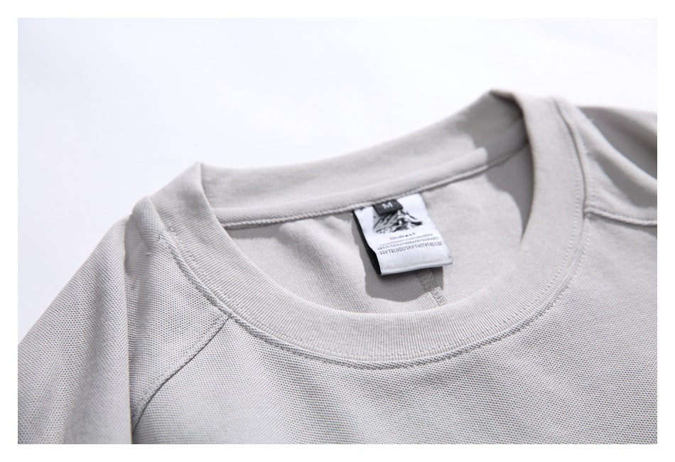 Close-up of the light gray T-shirt's crew neckline, shoulder stitching, and attached neck label.