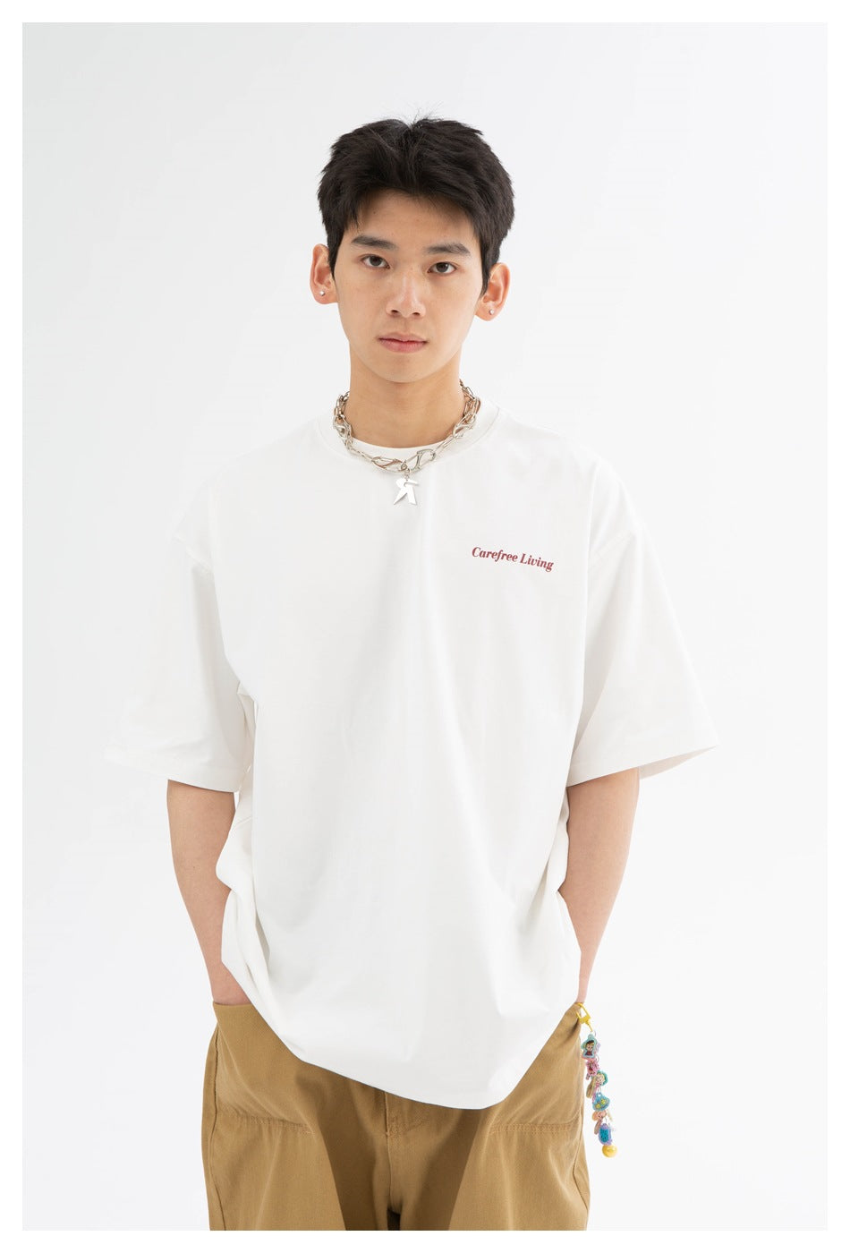 Close view of a model wearing a white T-shirt with small red chest lettering and a relaxed fit.