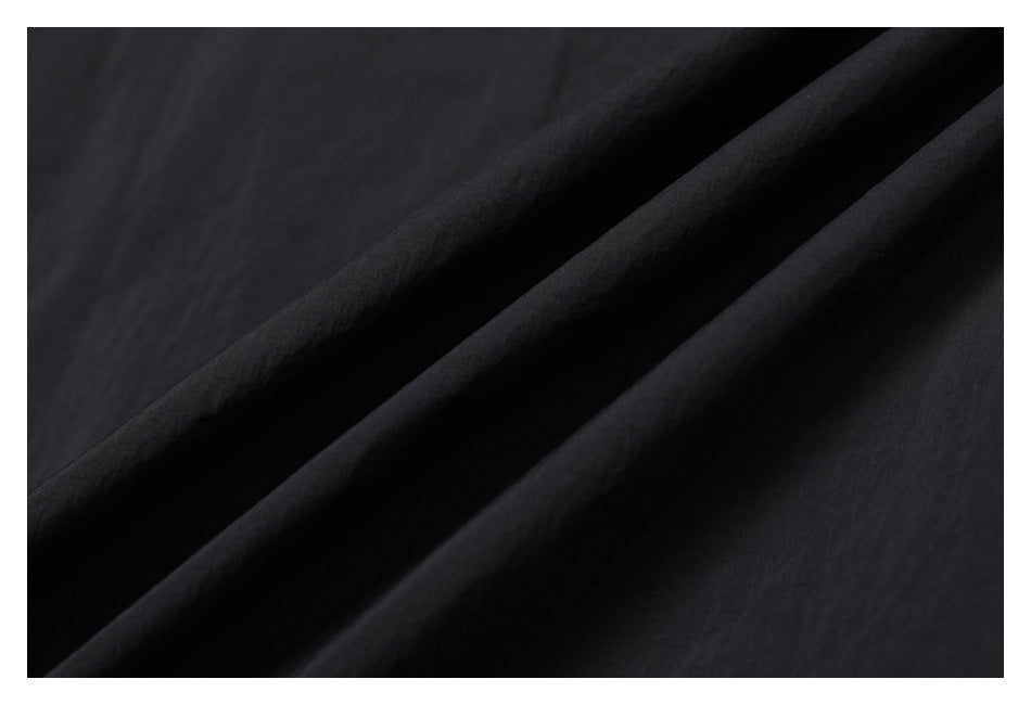 Close-up of black fabric arranged in broad diagonal folds.