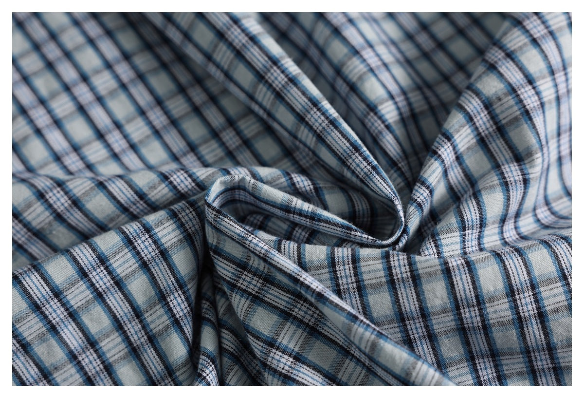 Close-up of loosely folded blue, gray, white, and black plaid fabric.