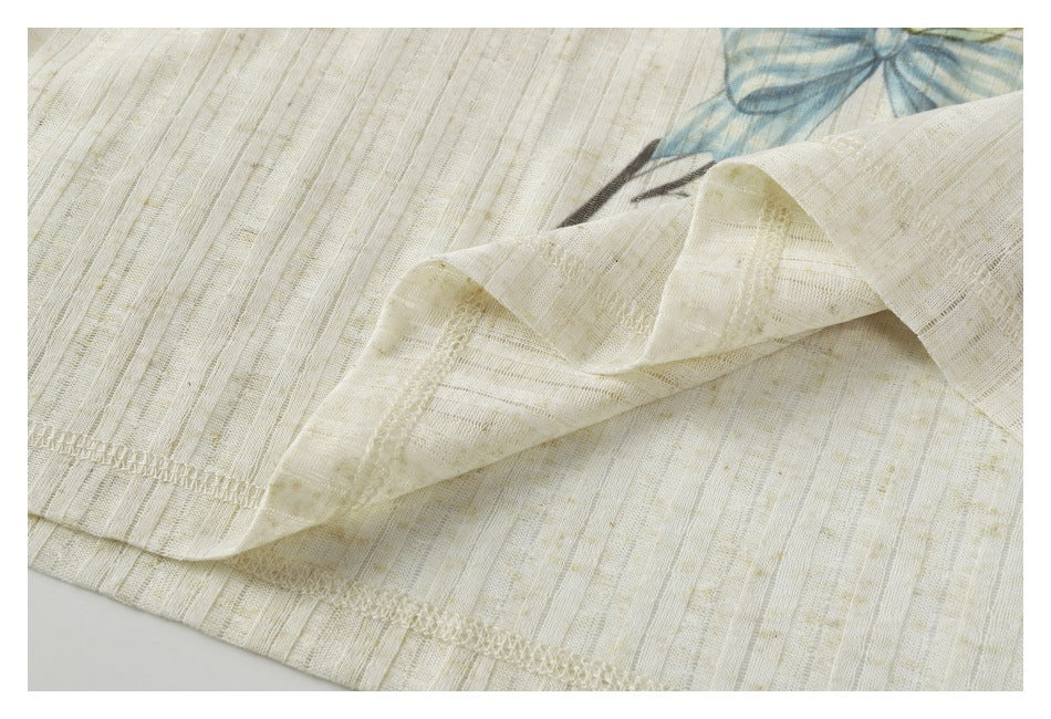 Close-up of the cream garment’s folded hem and overlock stitching, with part of its printed design visible.