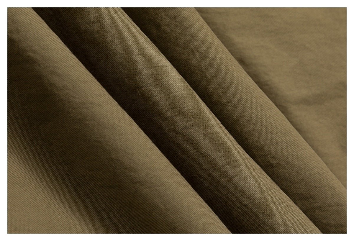 Close-up of olive-brown fabric folded into soft diagonal ridges, showing a fine ribbed texture.