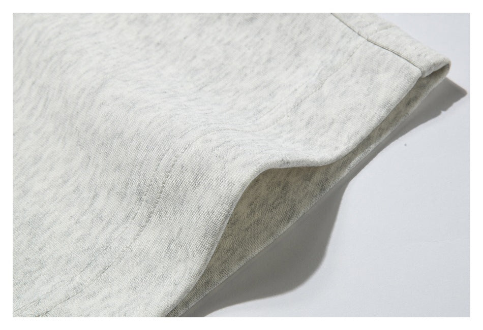 Close-up of a stitched edge and folded hem on light heather-gray sweatpants.