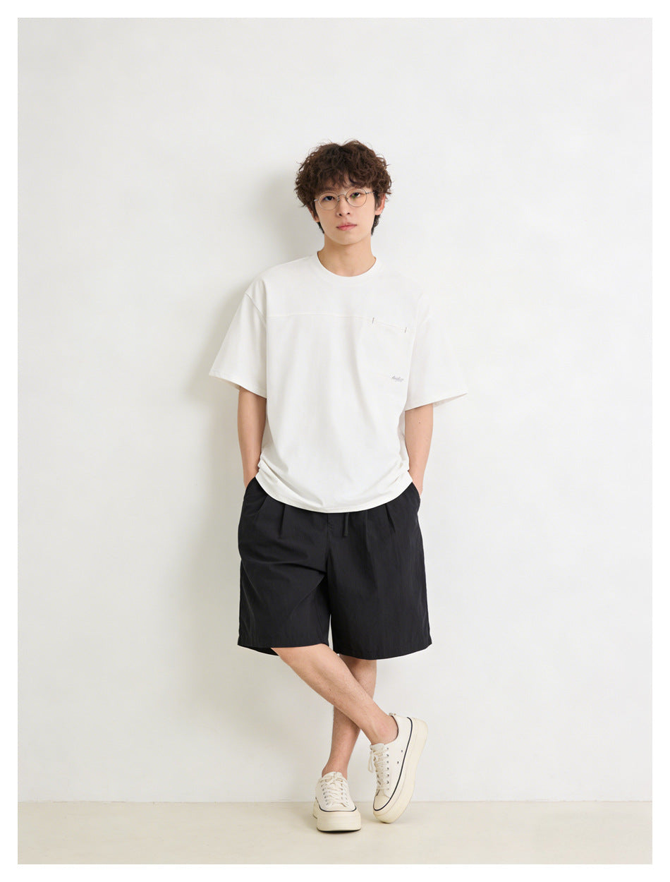 Model wearing a white short-sleeve T-shirt with a horizontal chest seam and black shorts, front view.