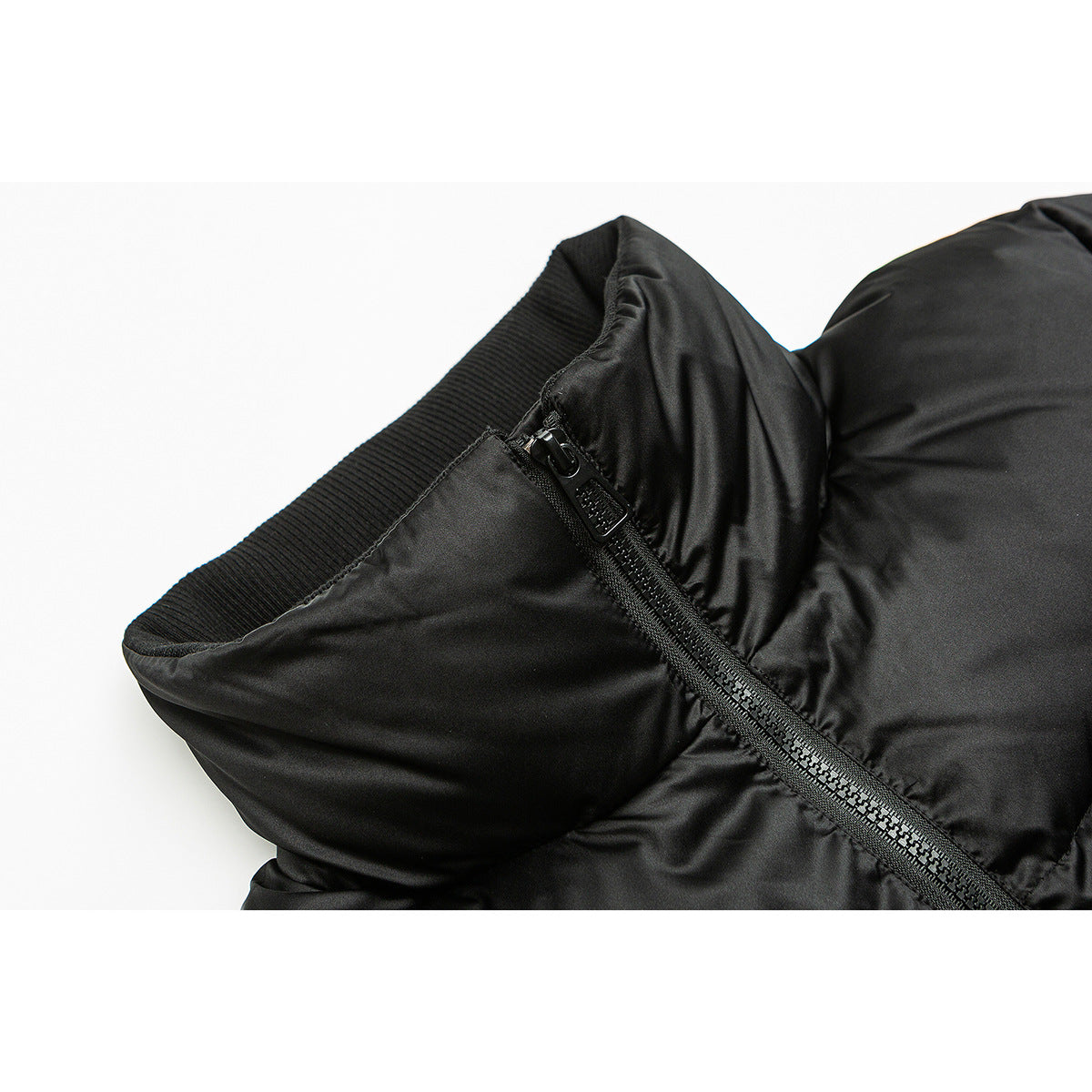 Close-up of a black padded jacket collar with a ribbed inner edge and diagonal zipper.