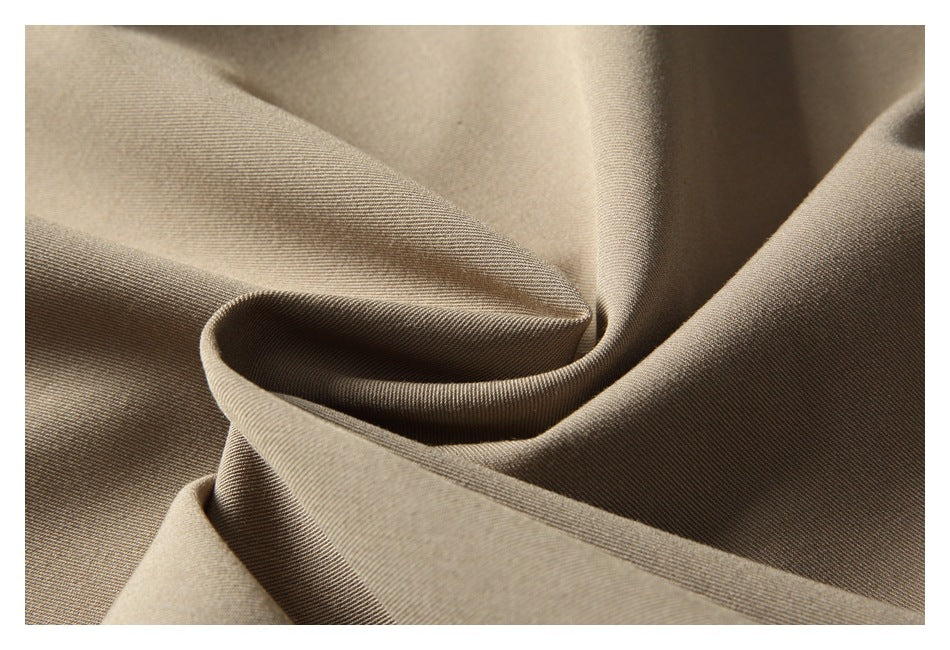 Close-up of taupe-brown fabric draped in soft folds, showing a fine diagonal weave.
