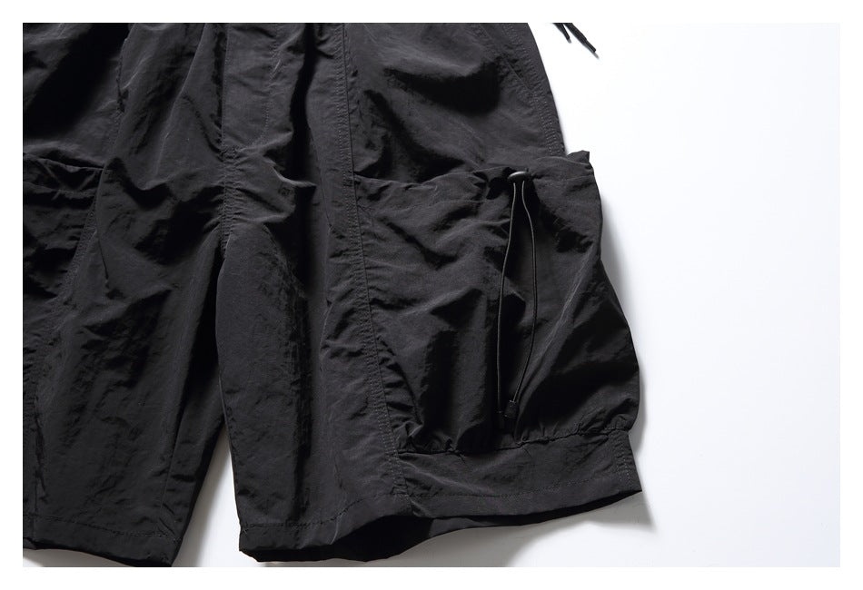 Close-up of a black shorts cargo pocket with an adjustable drawcord near the hem.