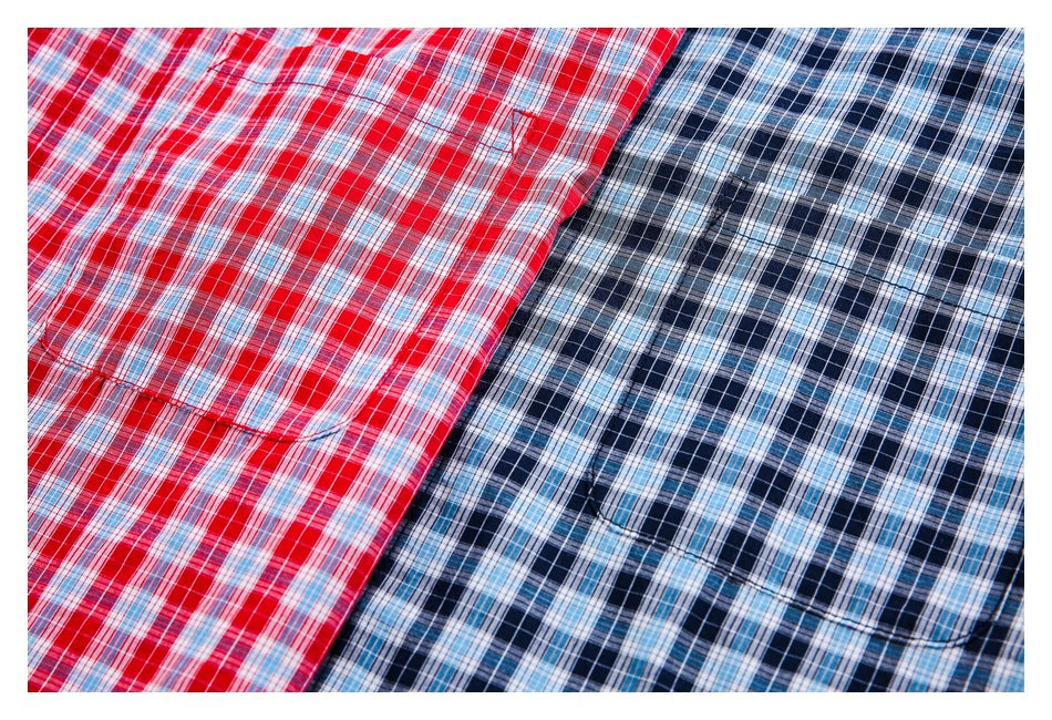 Close-up of the plaid fabric and chest pockets on red and blue button-up shirts.