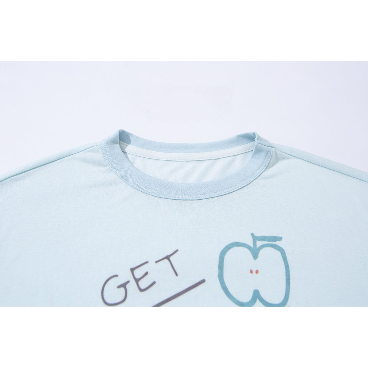Close-up of a pale blue crew-neck shirt showing the collar and part of its colorful handwritten-style graphic.