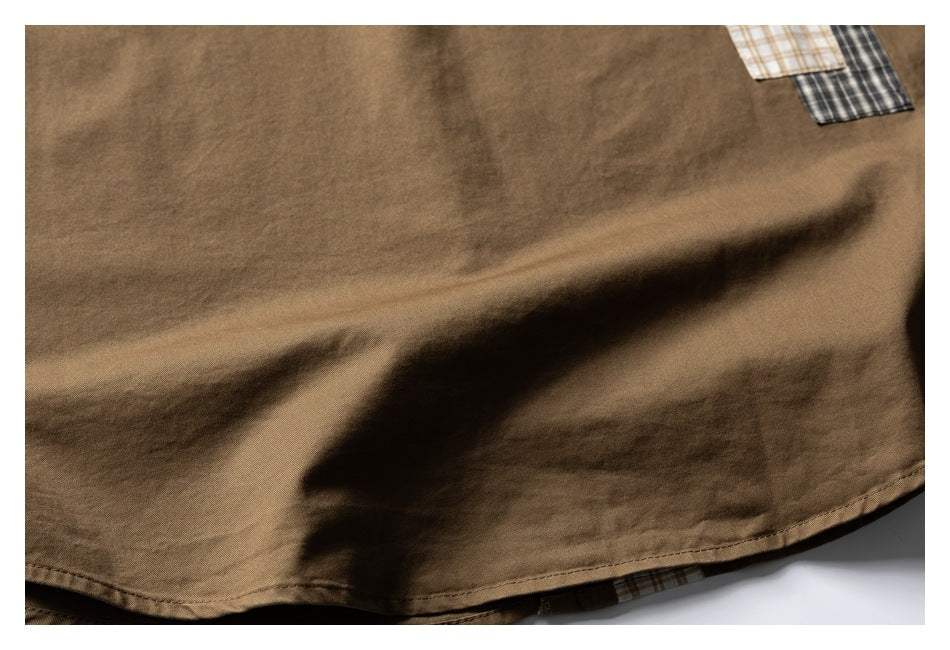 Close-up of the curved hem of a brown shirt with plaid fabric peeking beneath it.