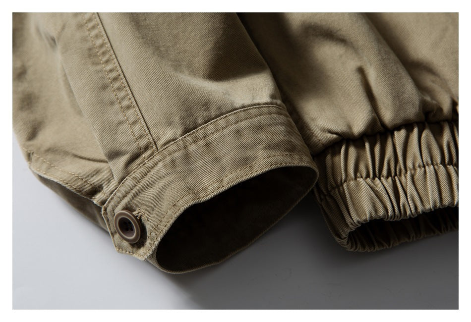 Close-up of a khaki jacket sleeve cuff with a button tab beside the gathered elastic hem.