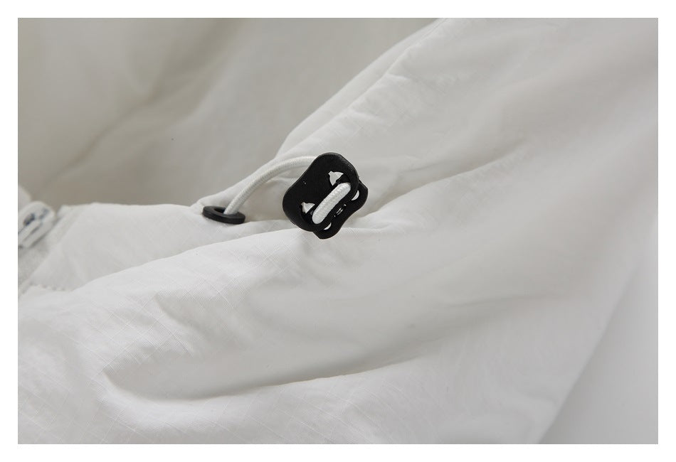 Close-up of a black drawcord toggle and cord on white jacket fabric.
